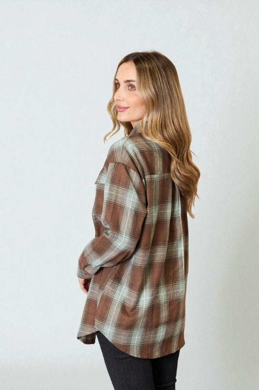 Woman wearing a brown plaid shirt against a white background