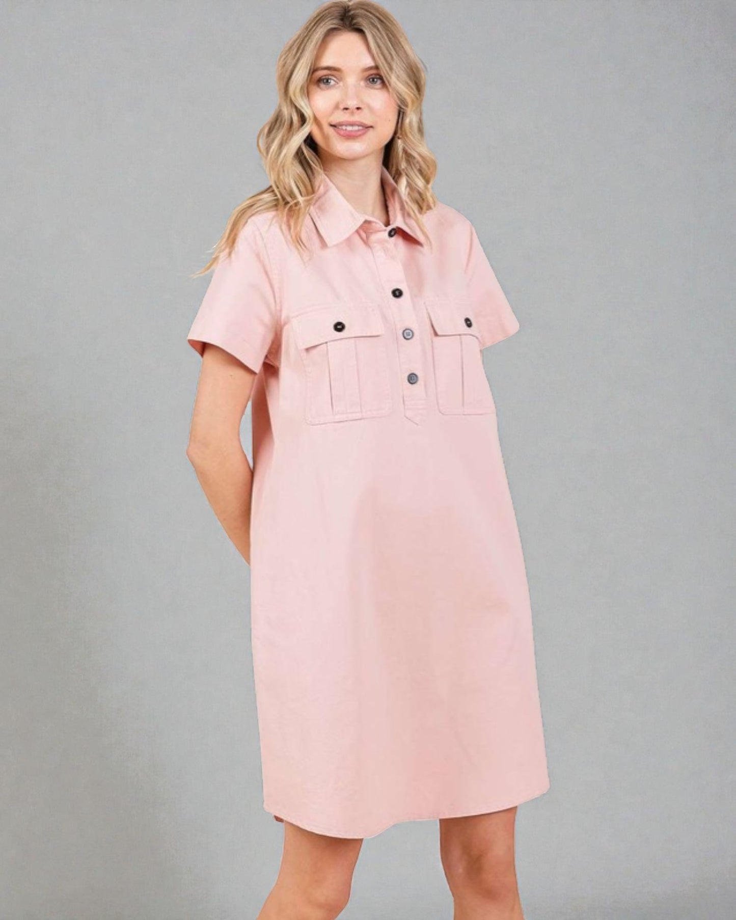 Woman wearing a pink dress with button details against a gray background
