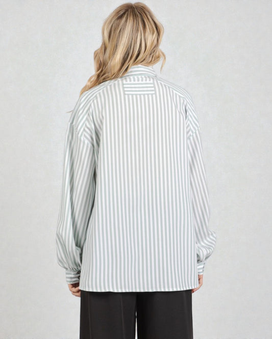 Person wearing a striped shirt with long sleeves on a plain background