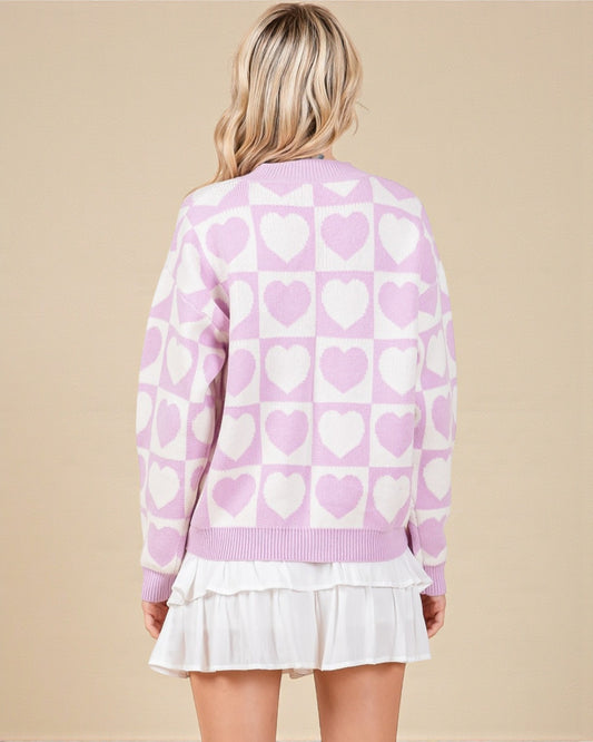 Person wearing a pink sweater with heart pattern on a beige background