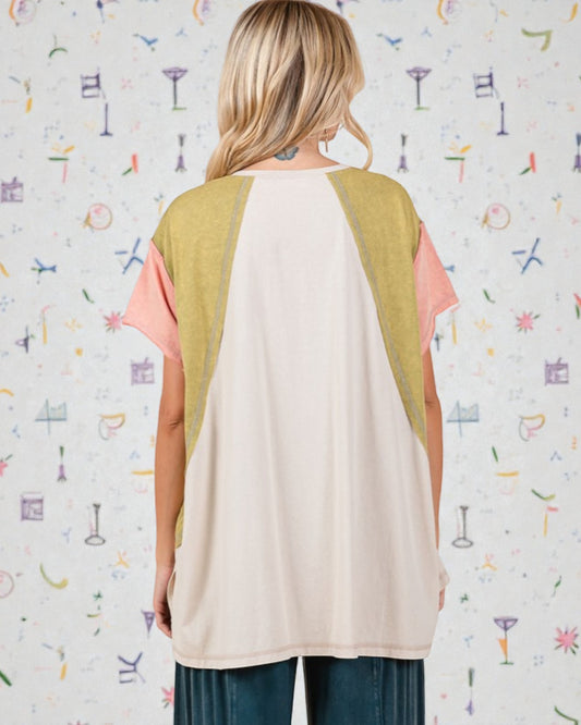 Woman wearing a sleeveless top with color-blocked design against a patterned wall.