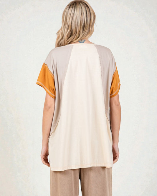 Woman wearing a beige and orange top with beige pants on a white background