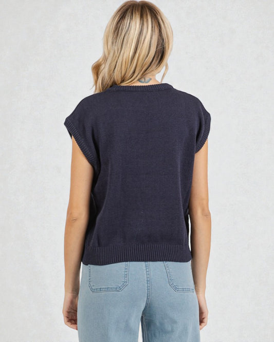 Person wearing a navy sleeveless sweater against a light background