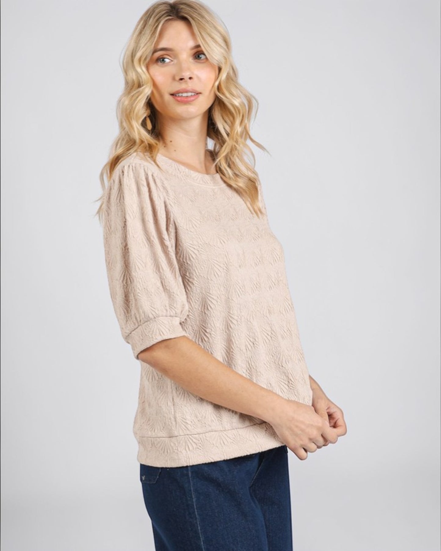 Woman wearing a beige sweater and blue jeans on a white background