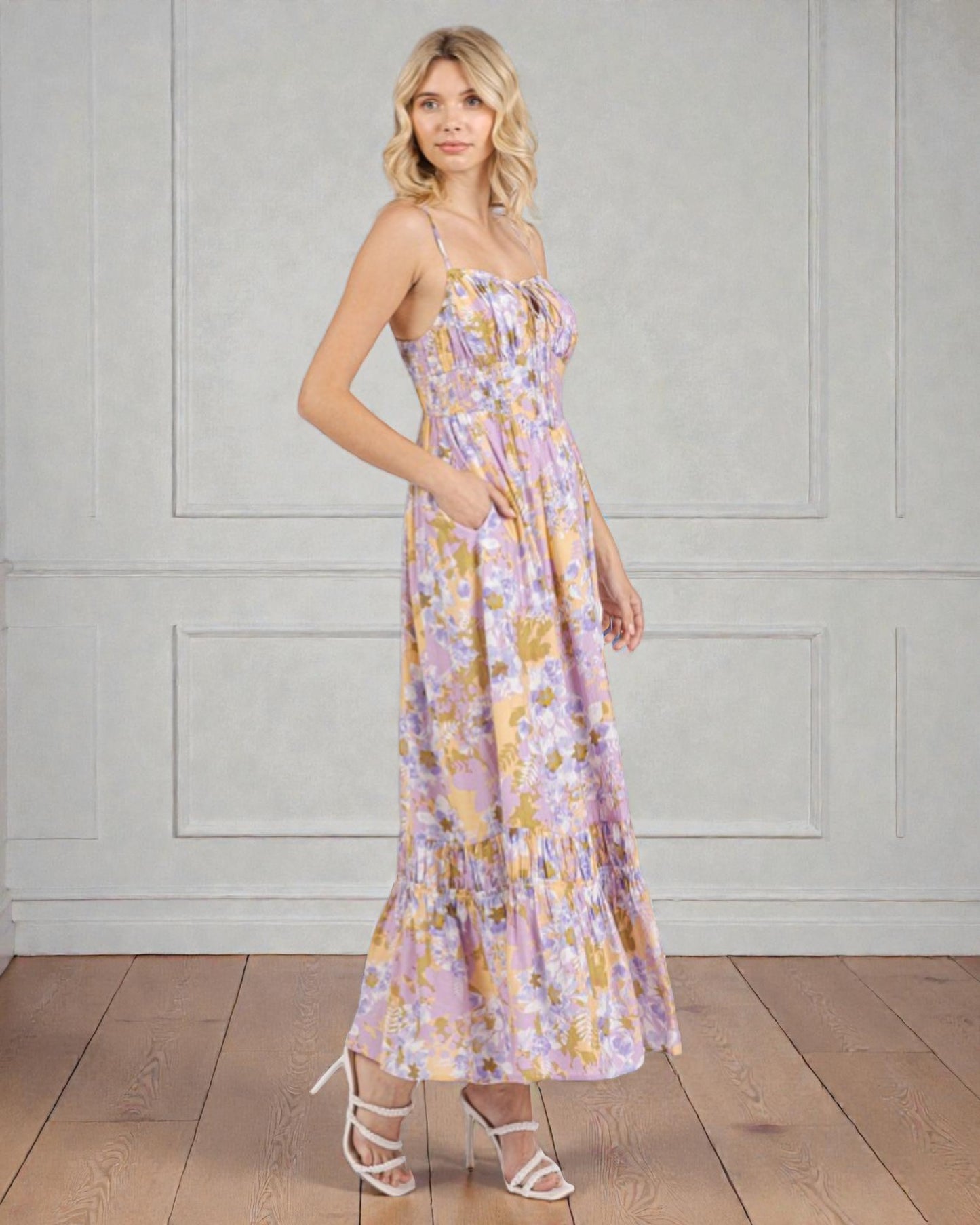 Woman wearing a floral dress standing against a plain wall.