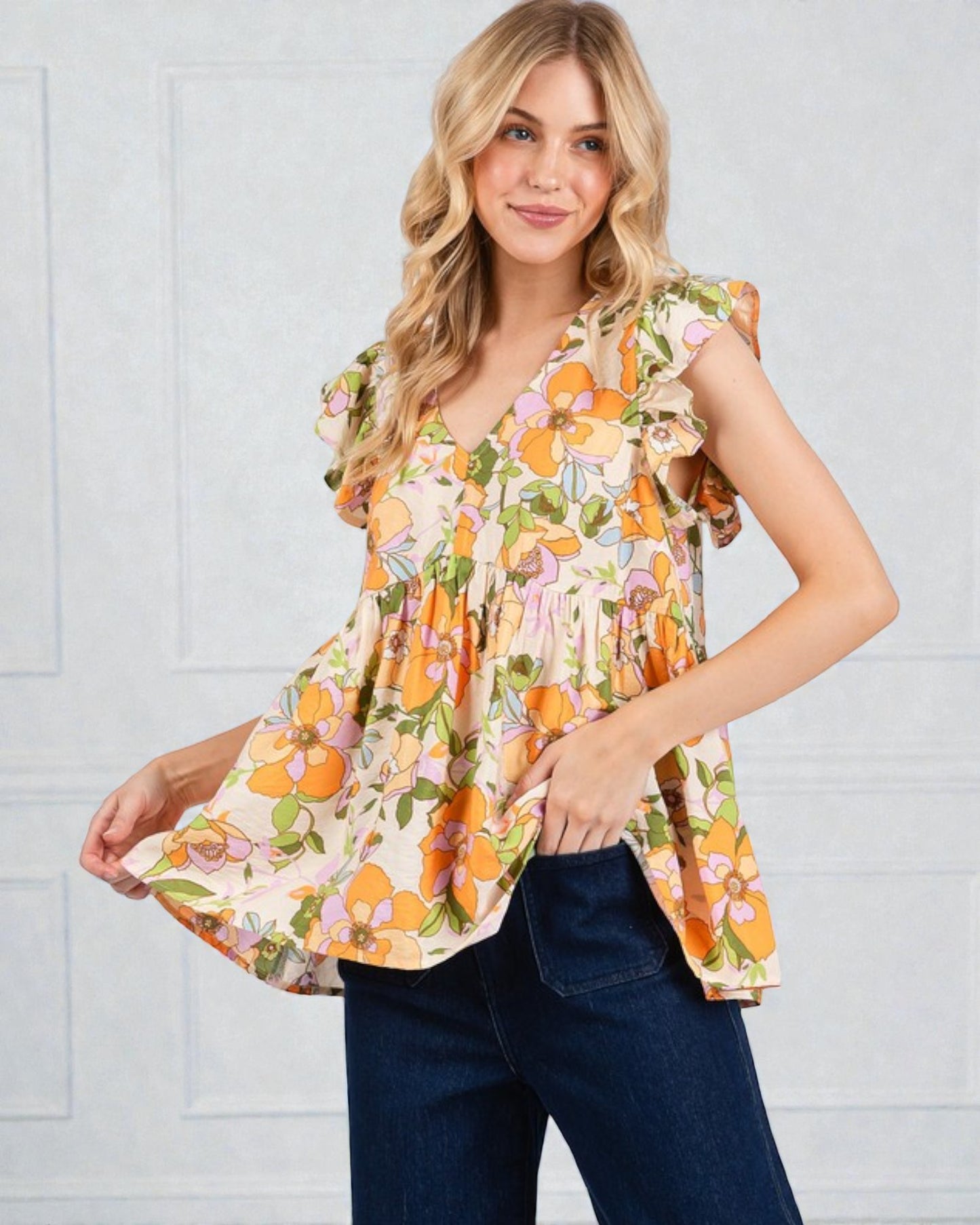 Woman wearing a floral blouse with orange and green pattern against a white background
