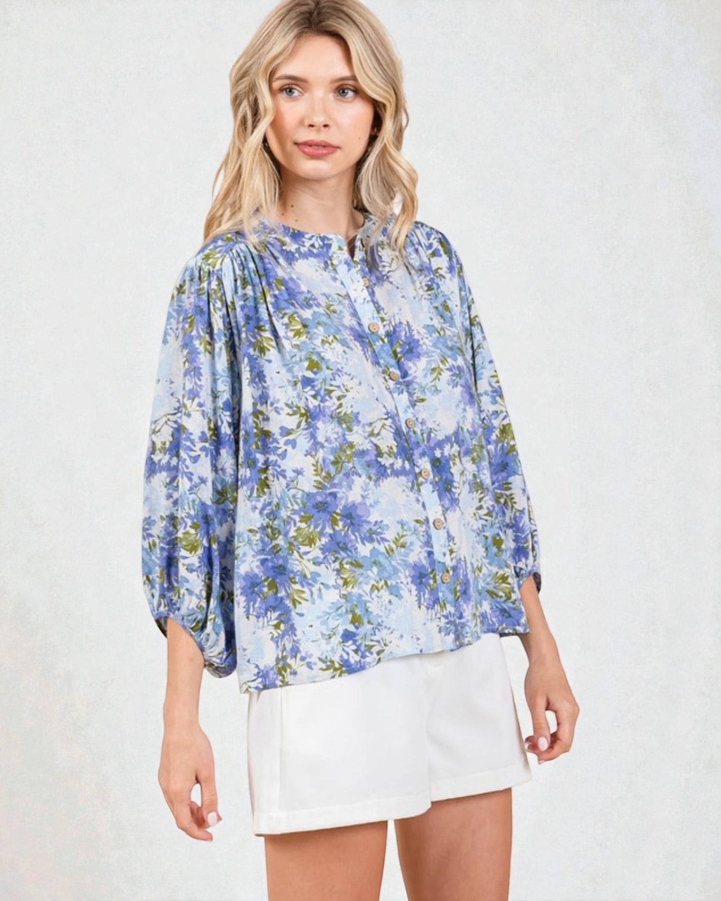 Woman wearing a blue floral blouse and white skirt on a light background