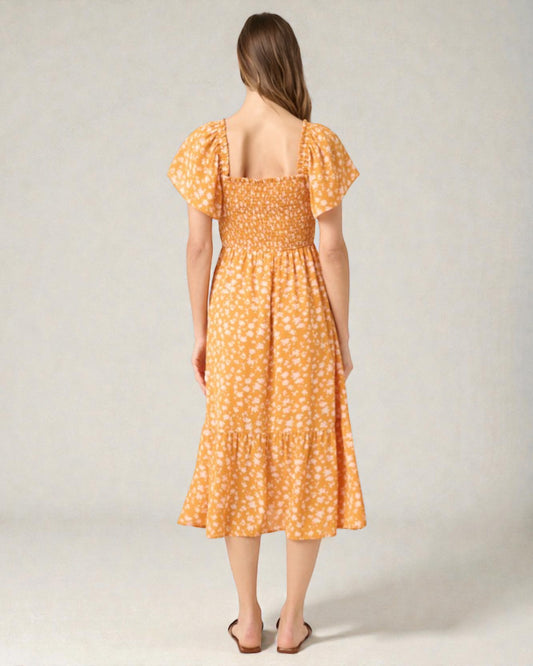 Woman wearing an orange floral dress against a plain background