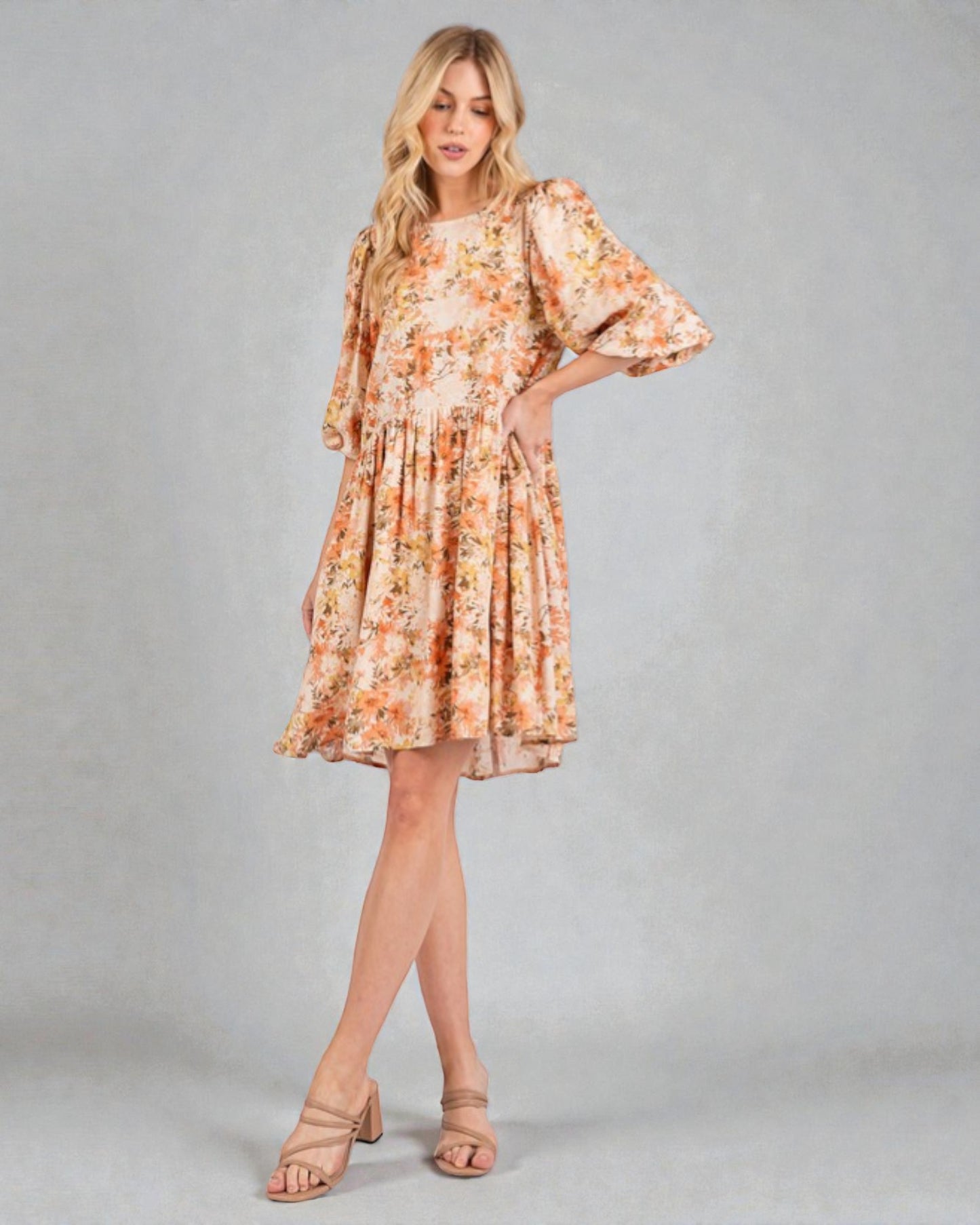 Woman wearing a floral dress with bell sleeves on a plain background