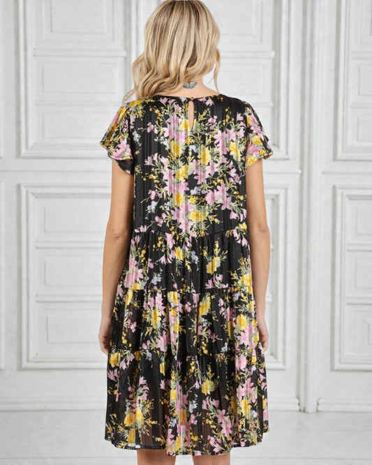Woman wearing a floral dress against a white paneled wall