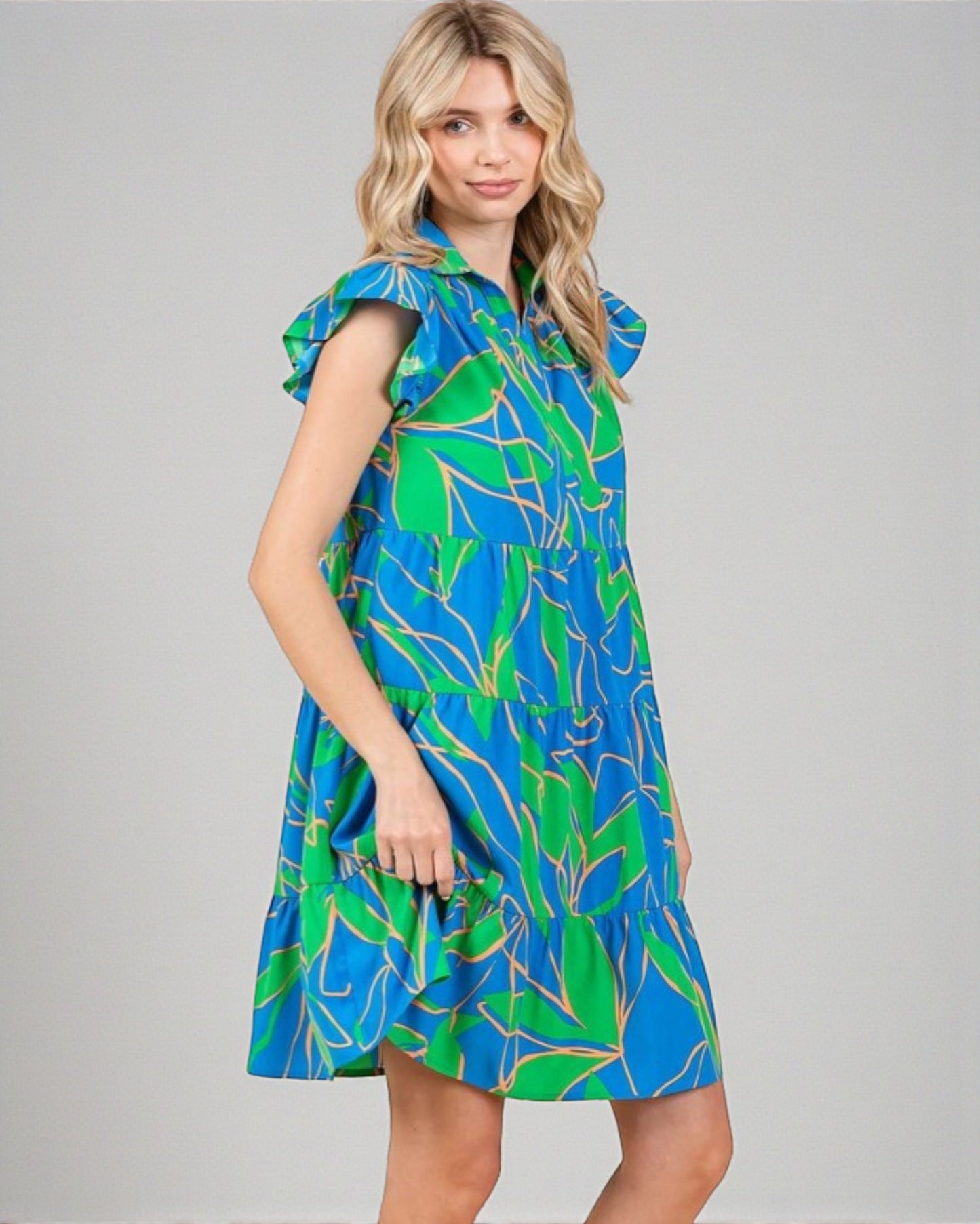 Woman wearing a blue and green patterned dress on a gray background