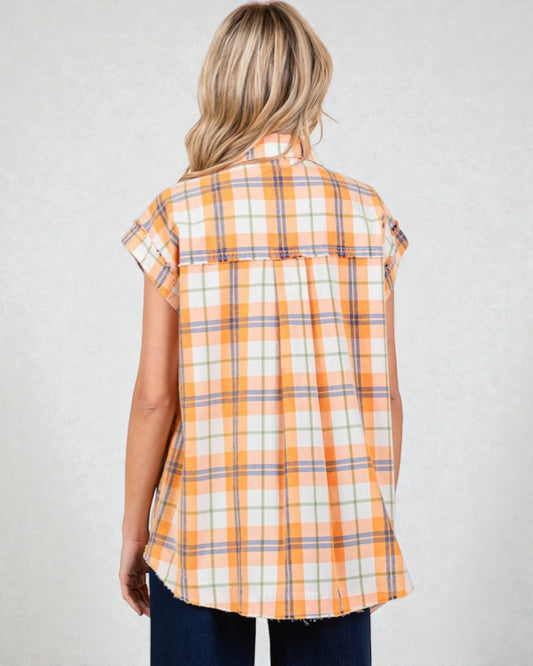 Woman wearing a sleeveless plaid shirt with orange and white pattern on a plain background