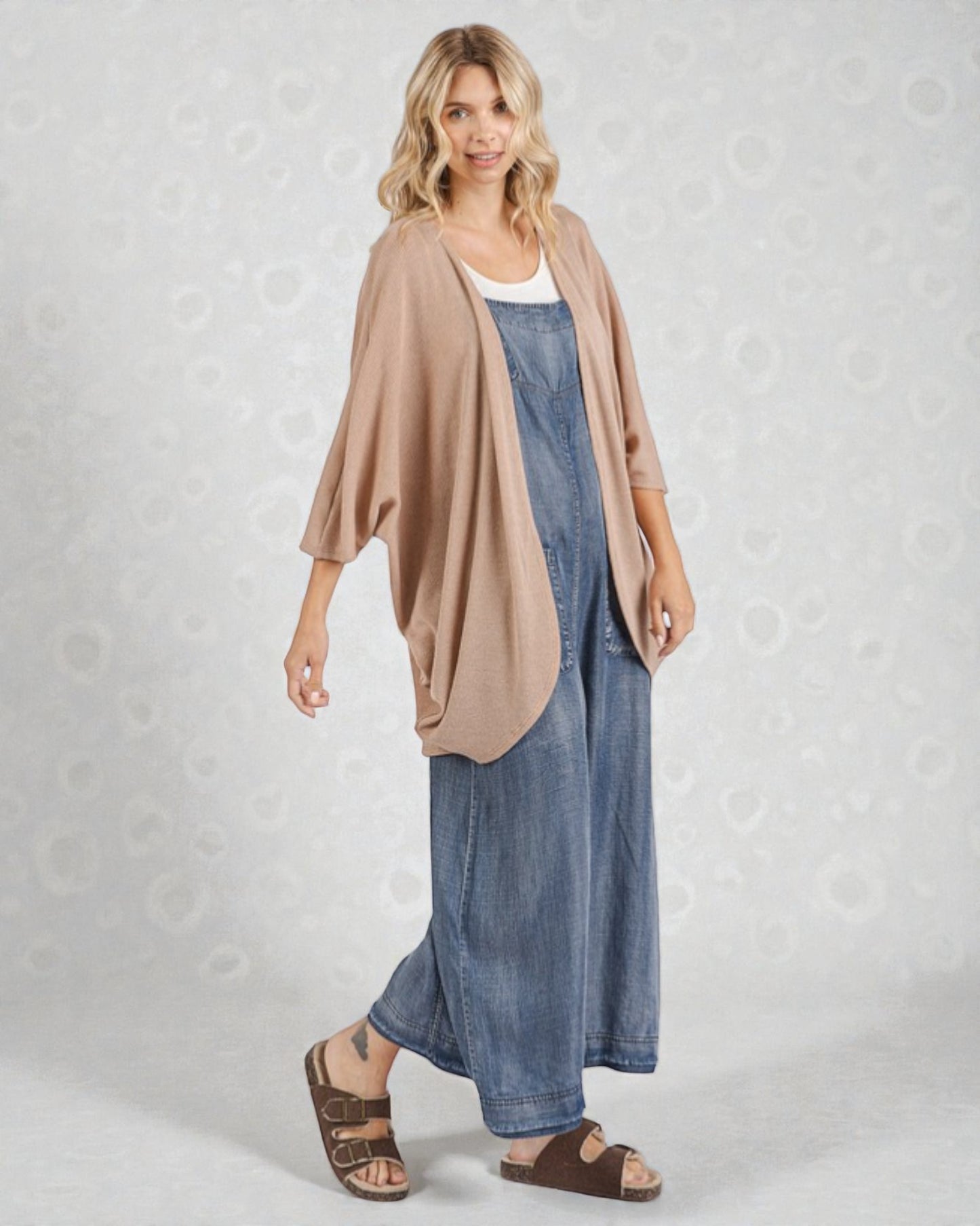 Woman wearing a beige cardigan and blue denim dress on a light gray background