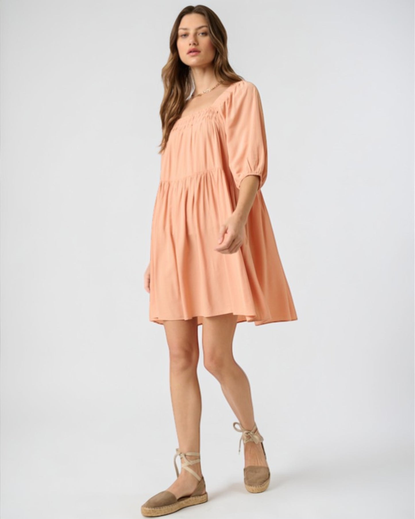 Woman wearing a peach-colored dress on a white background