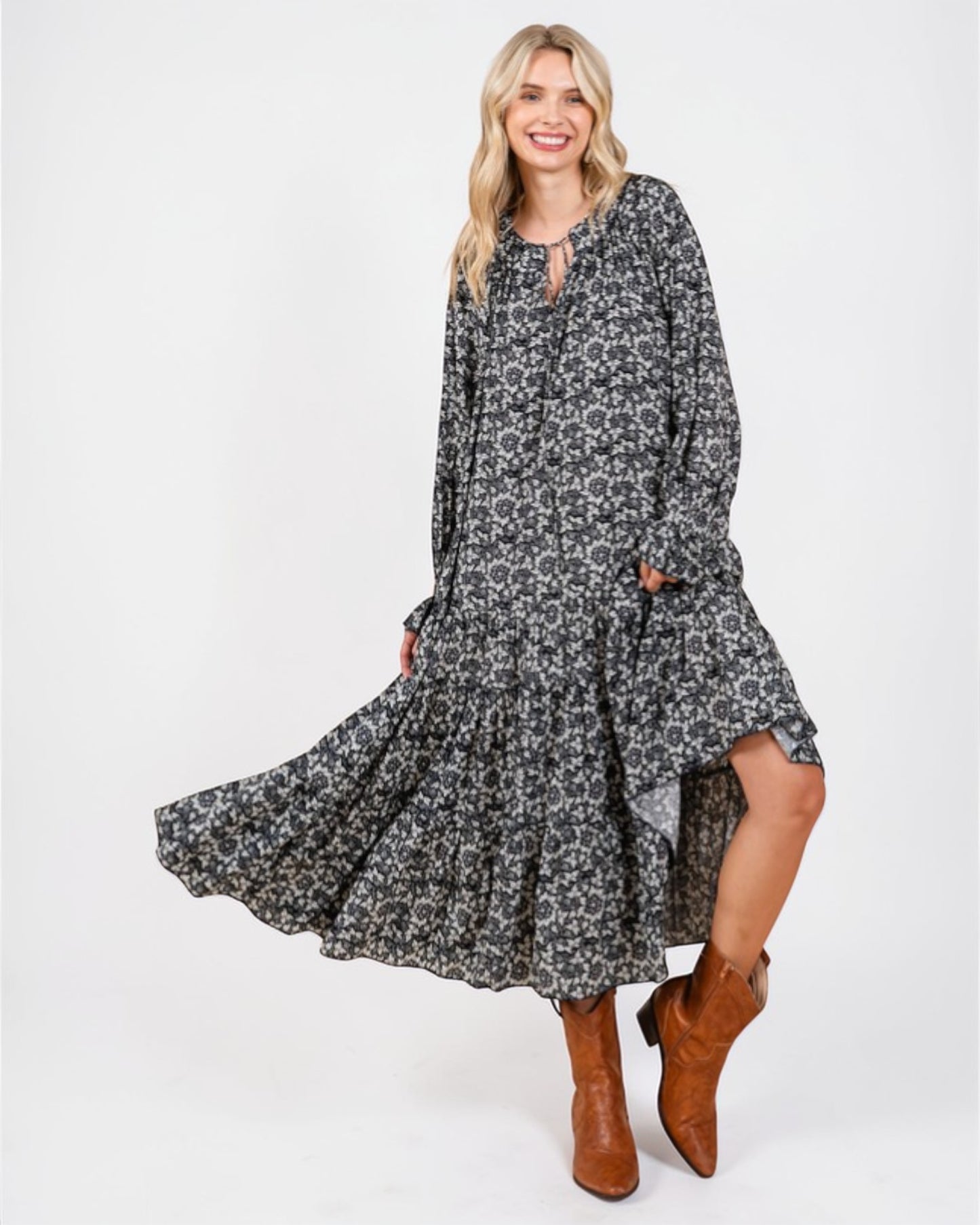 Woman wearing a floral dress with long sleeves and brown boots on a white background