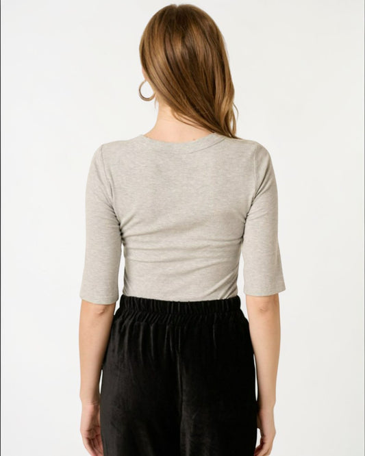 Person wearing a gray cropped top and black pants on a white background