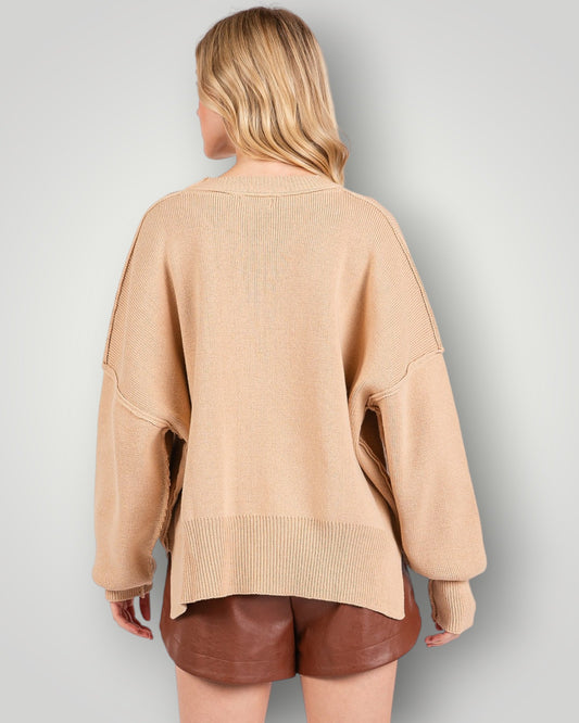 Person wearing a beige sweater and brown shorts on a plain background
