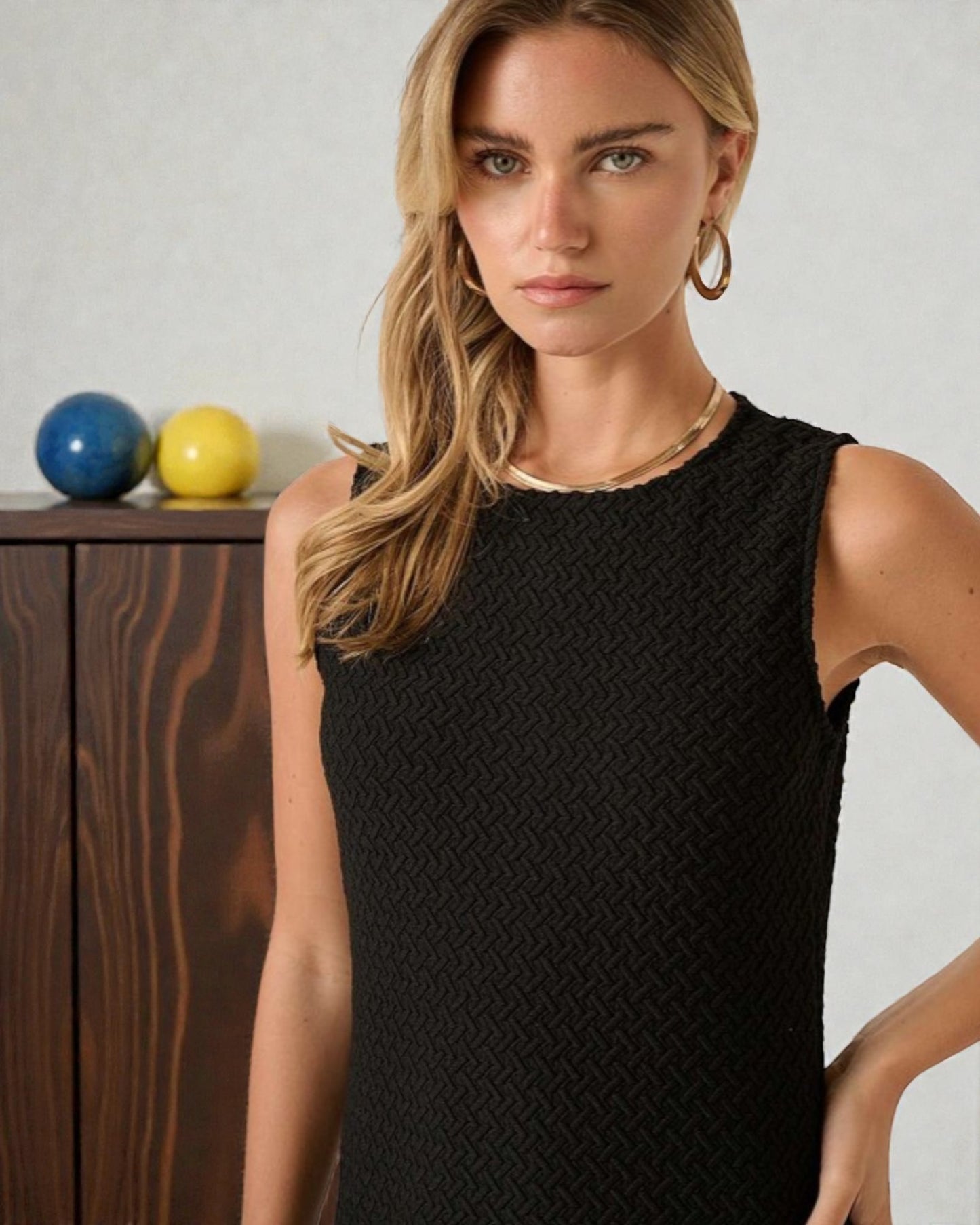 Woman wearing a black sleeveless top with a neutral background
