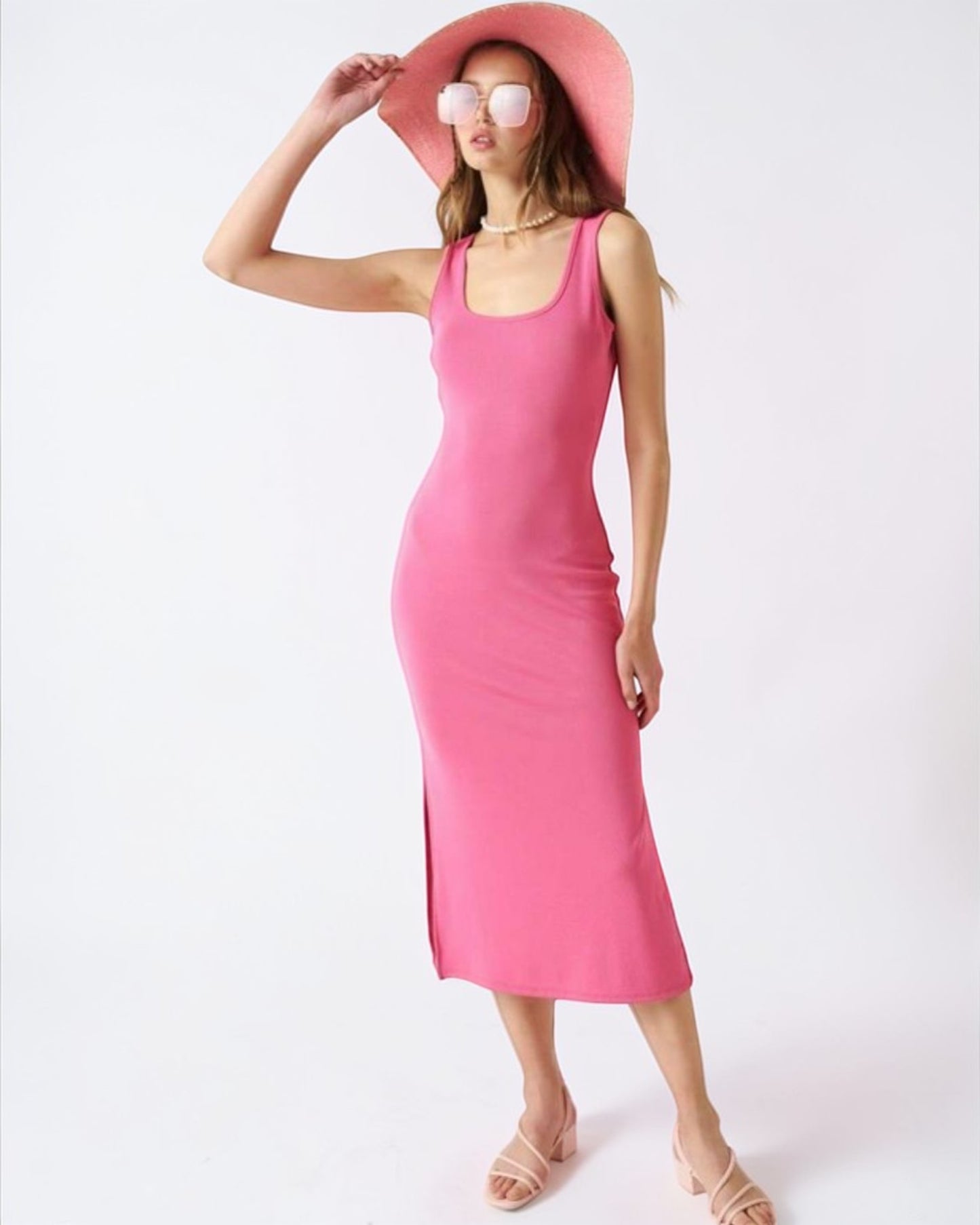 Woman wearing a pink dress and hat on a white background