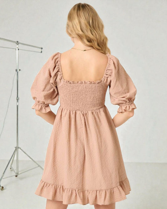 Woman wearing a pink dress with puff sleeves against a white background