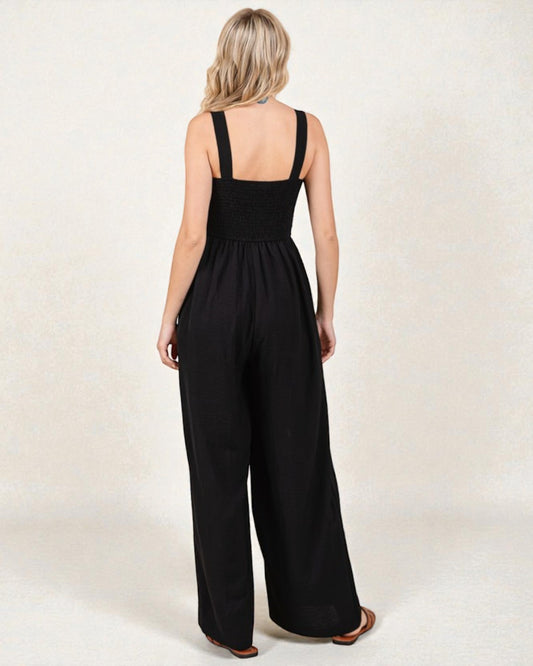 Woman wearing a black jumpsuit on a plain background