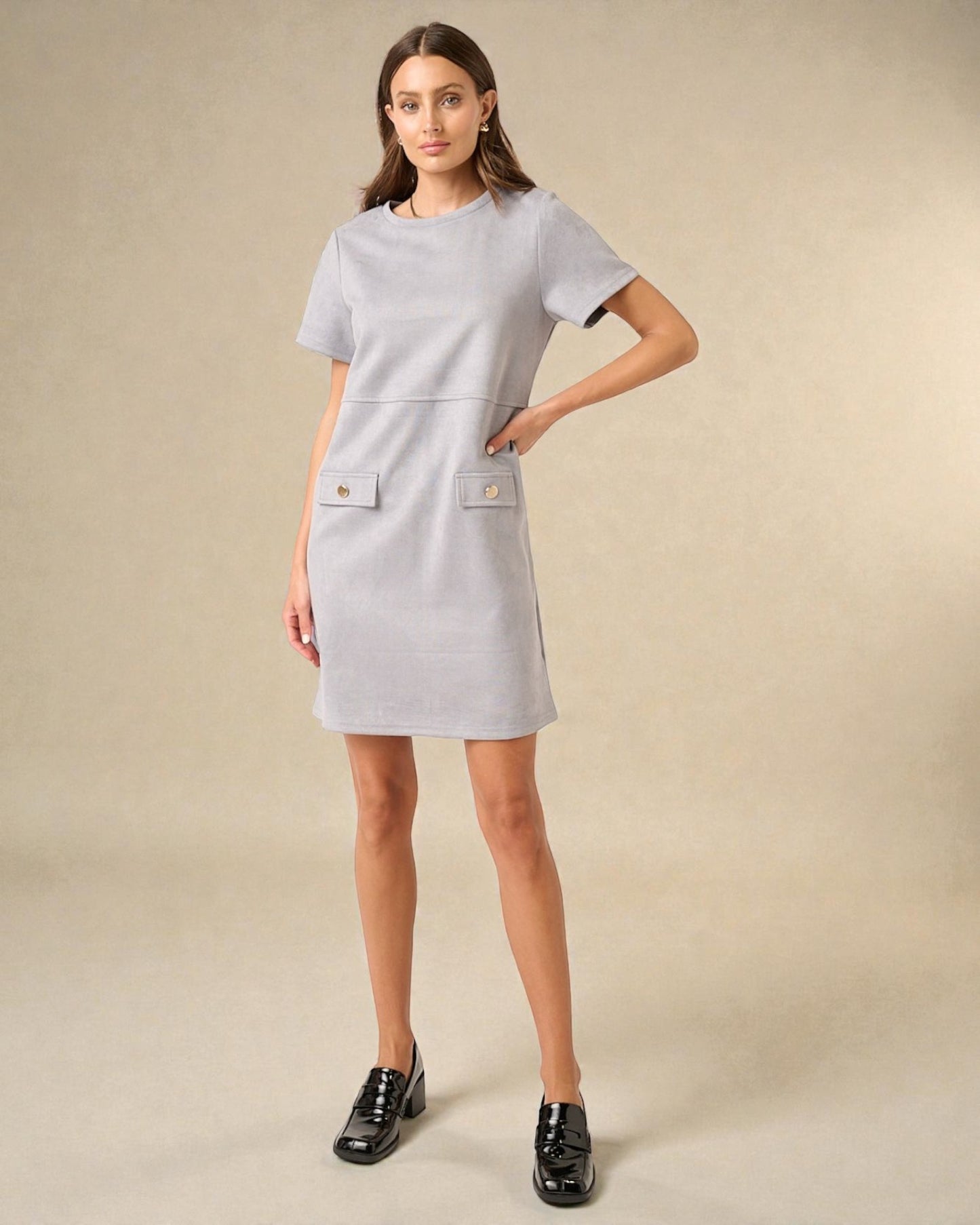 Woman wearing a gray dress with button details on a beige background