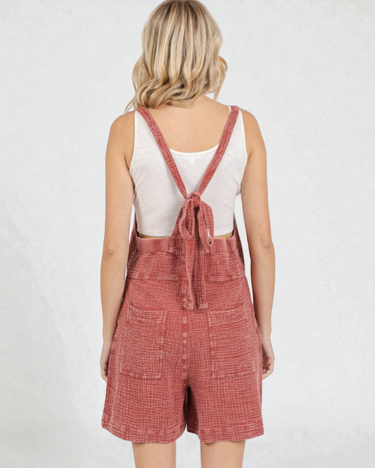 Person wearing red checkered overalls on a white background