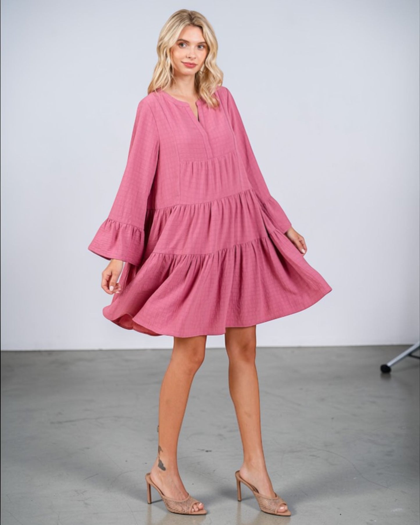 Woman wearing a pink dress with long sleeves on a plain background