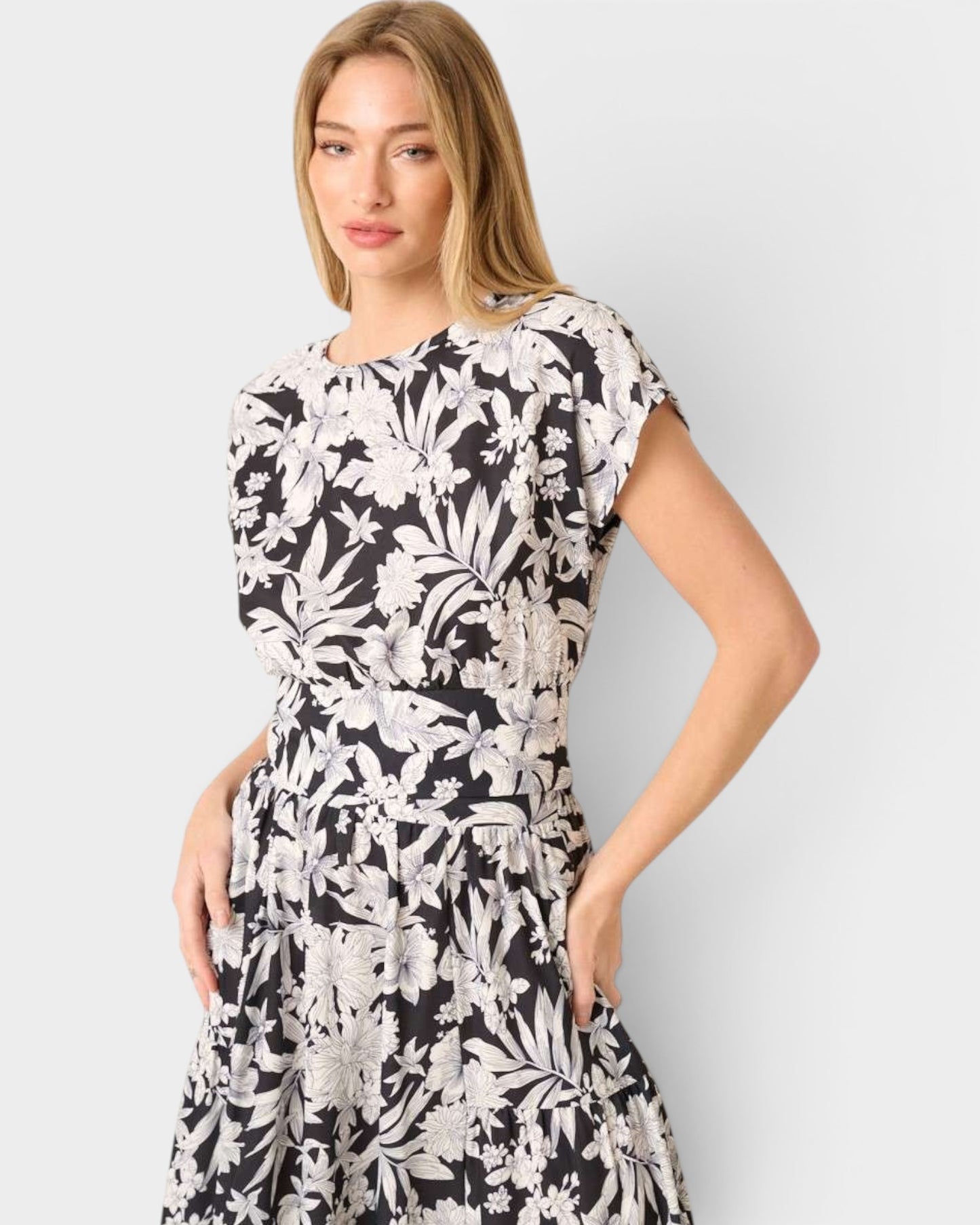 Woman wearing a black and white floral dress against a plain background