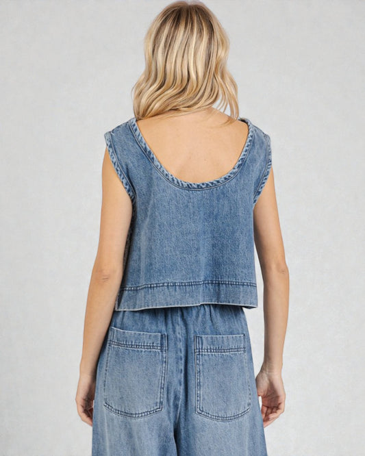 Woman wearing a denim sleeveless top and pants on a plain background