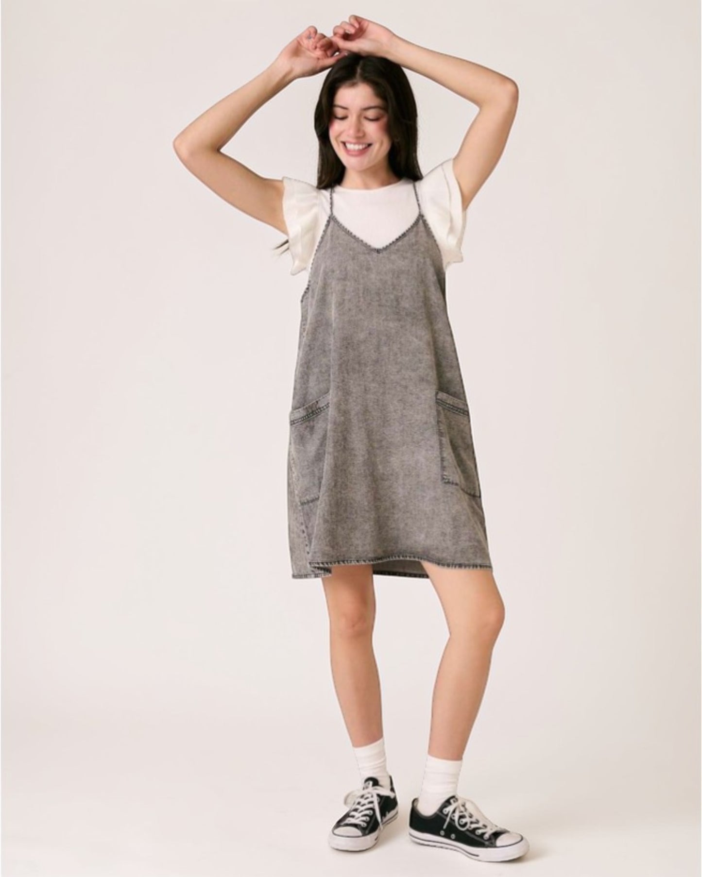 Woman wearing a gray dress with white sleeves against a plain background