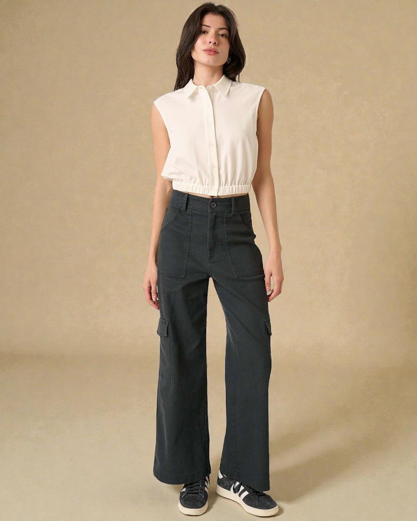 Woman wearing a white blouse and dark pants on a beige background