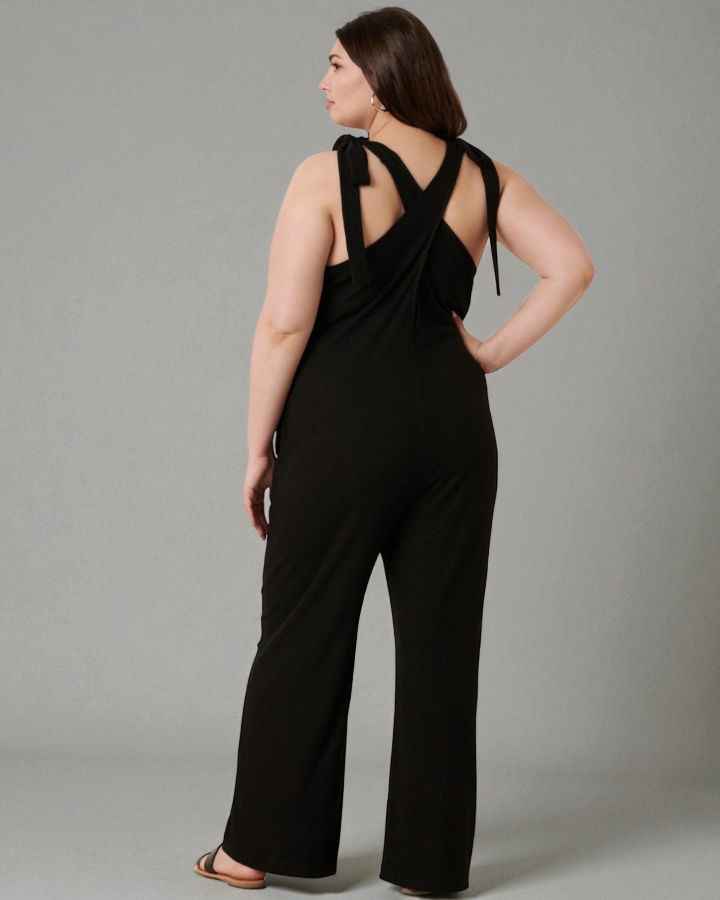 Woman wearing a black jumpsuit with a gray background