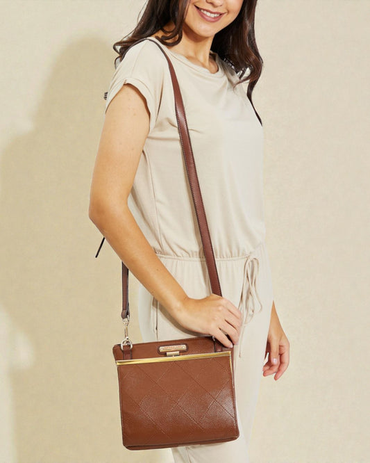 Woman holding a brown handbag against a plain background