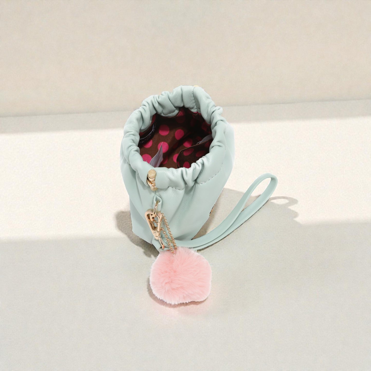 Light blue pouch with pink pom-pom on a white background