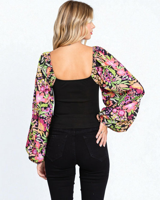 Woman wearing a colorful floral kimono over a black outfit on a white background
