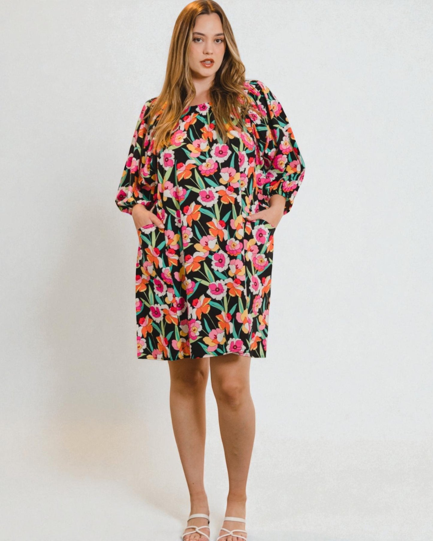Woman wearing a colorful floral dress against a plain background