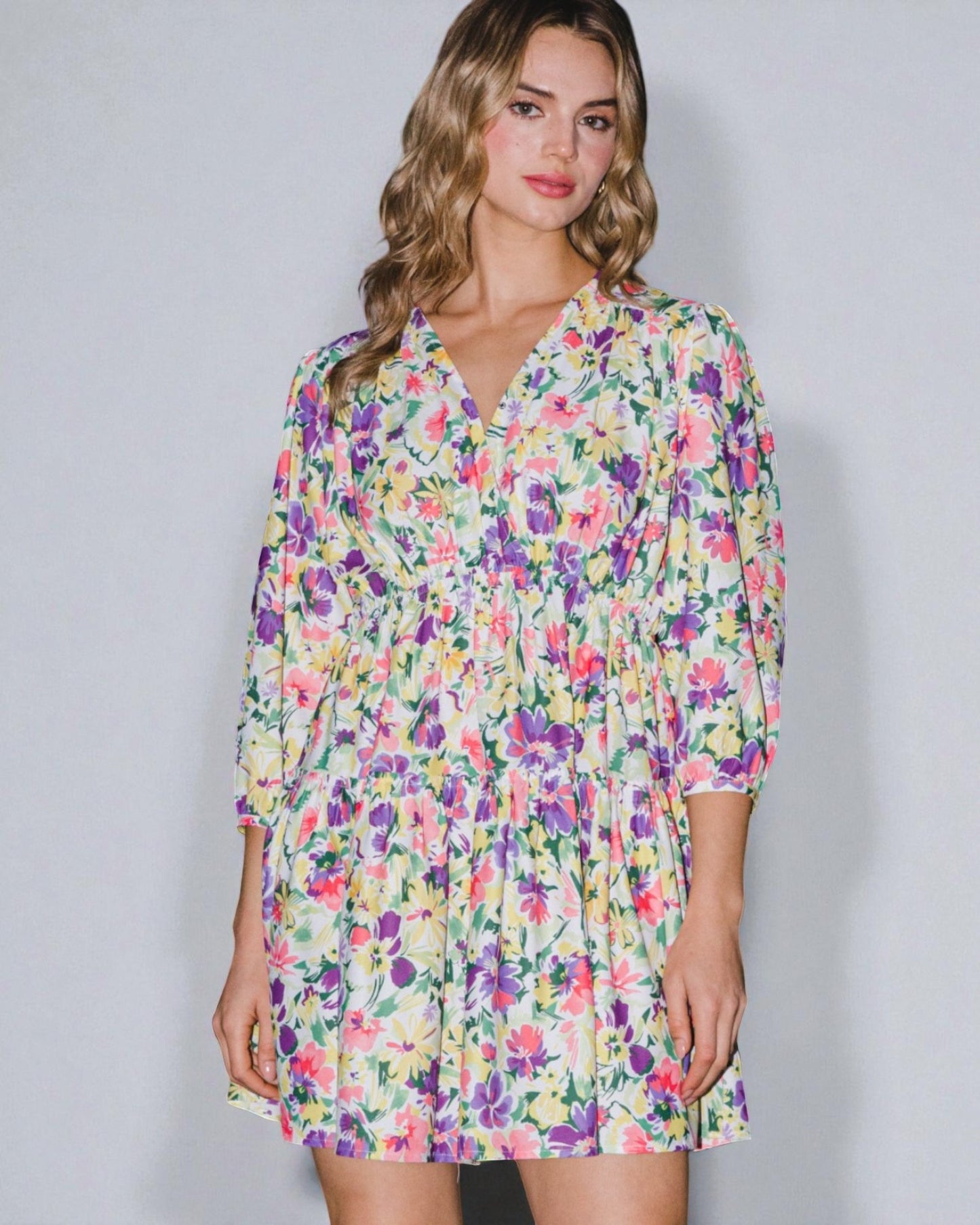 Woman wearing a colorful floral dress against a plain background