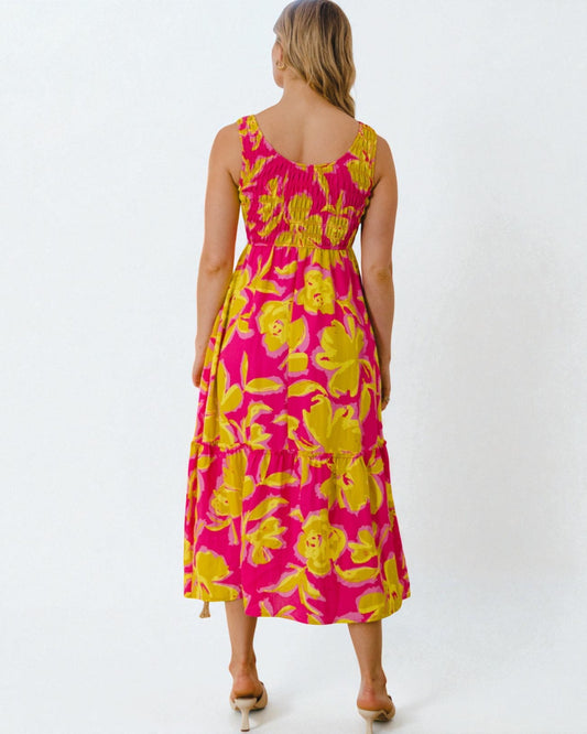 Woman wearing a pink and yellow floral dress on a white background