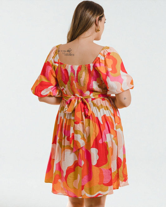 Woman wearing a colorful patterned dress on a white background