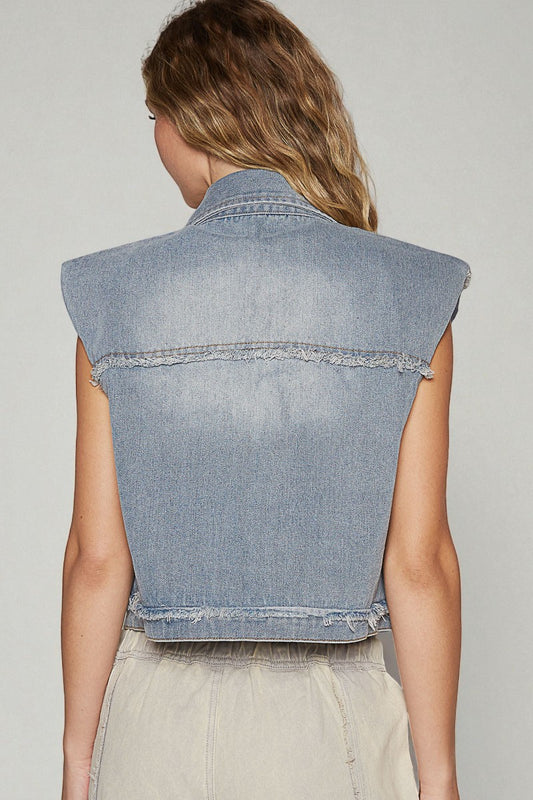 Denim vest worn by a person on a plain background