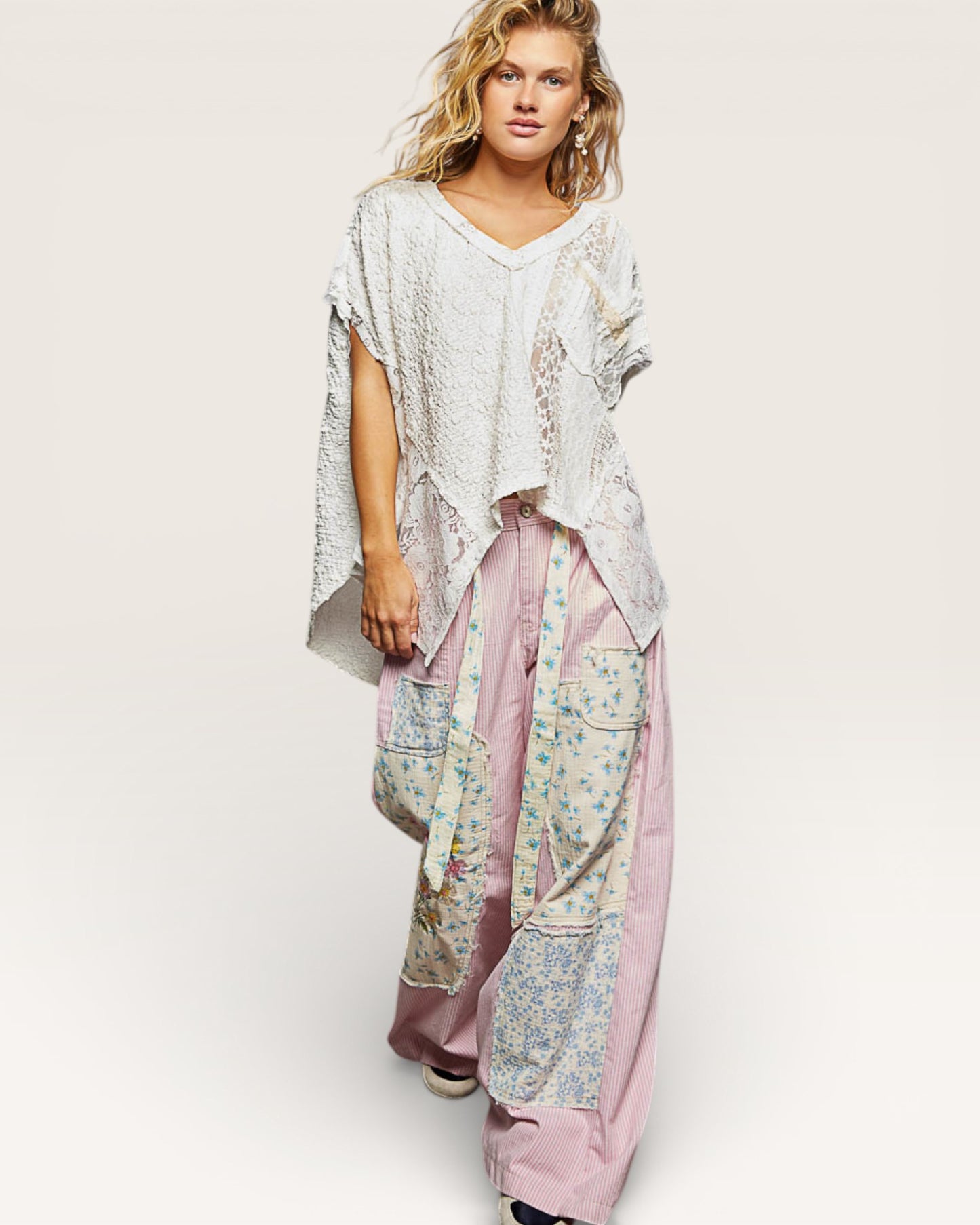 Woman wearing a light-colored top and patterned pants on a white background