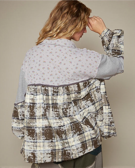 Person wearing a plaid jacket over a patterned shirt against a beige background