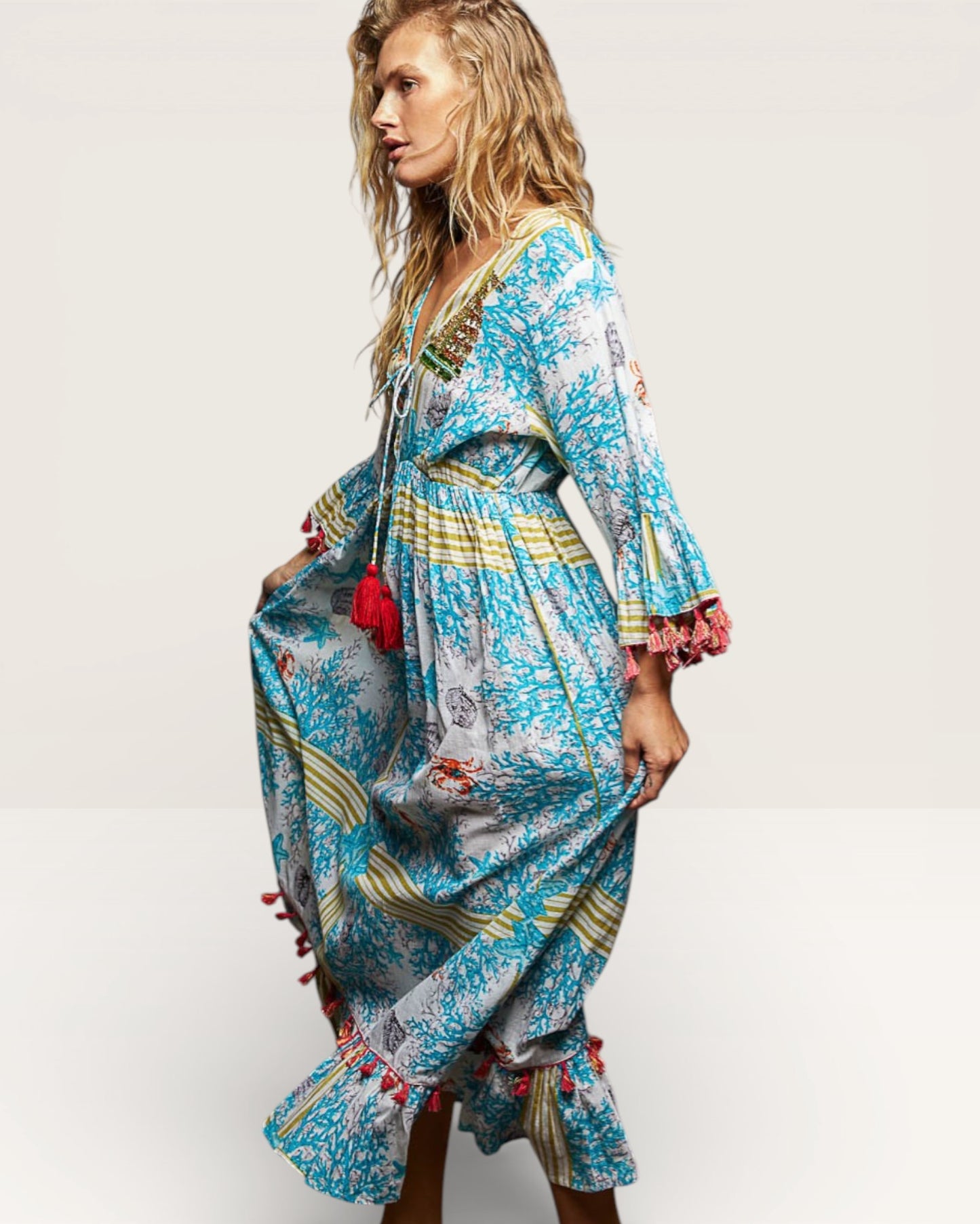 Woman wearing a colorful dress with patterns and tassels on a white background
