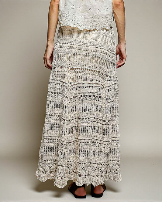 Person wearing a long, patterned skirt with a plain background