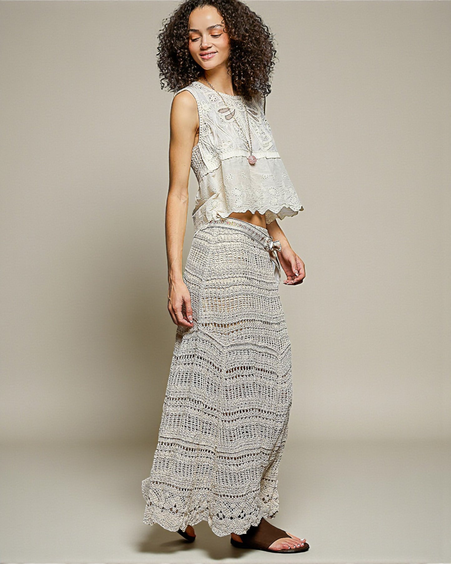 Woman wearing a white lace top and skirt on a plain background