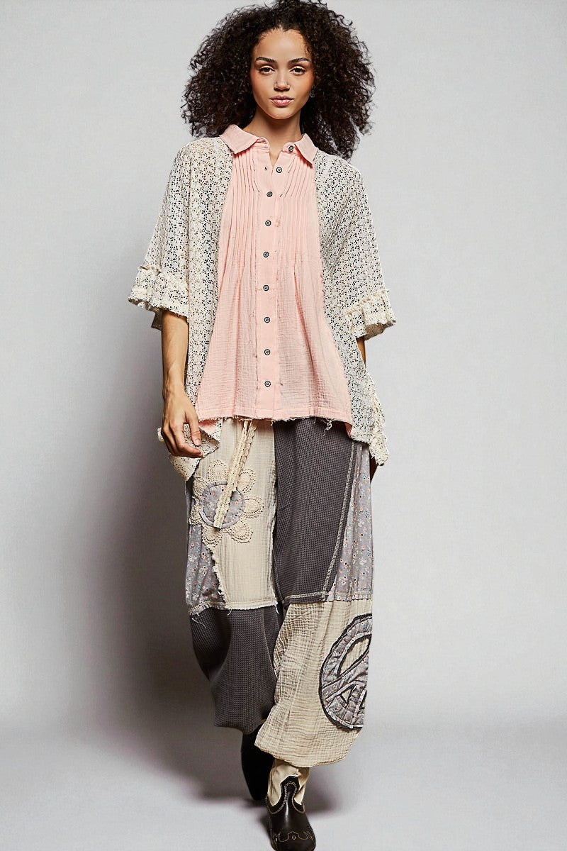 Woman wearing a layered outfit with a pink shirt, patterned jacket, and patchwork skirt on a plain background