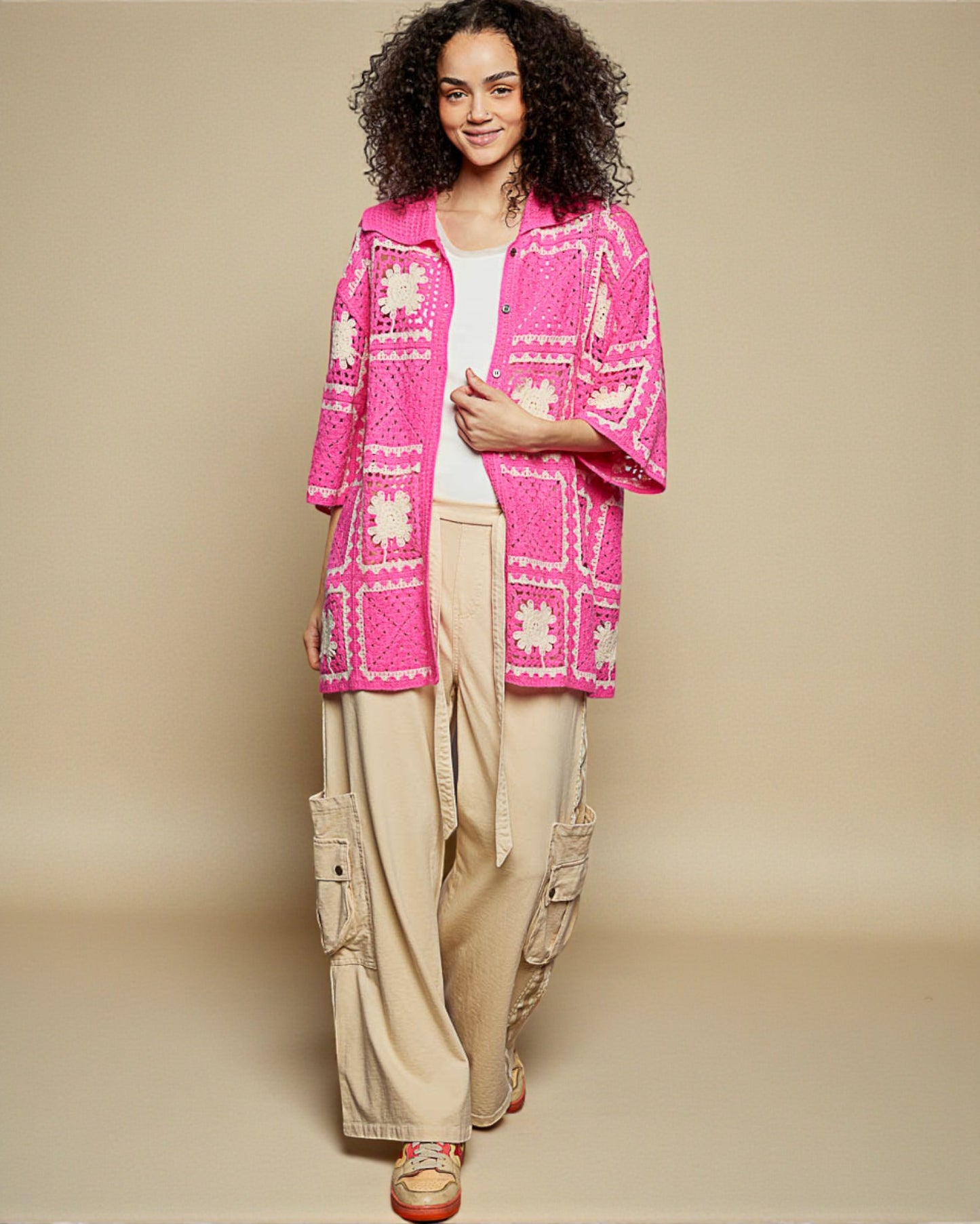 Woman wearing a bright pink patterned jacket on a beige background