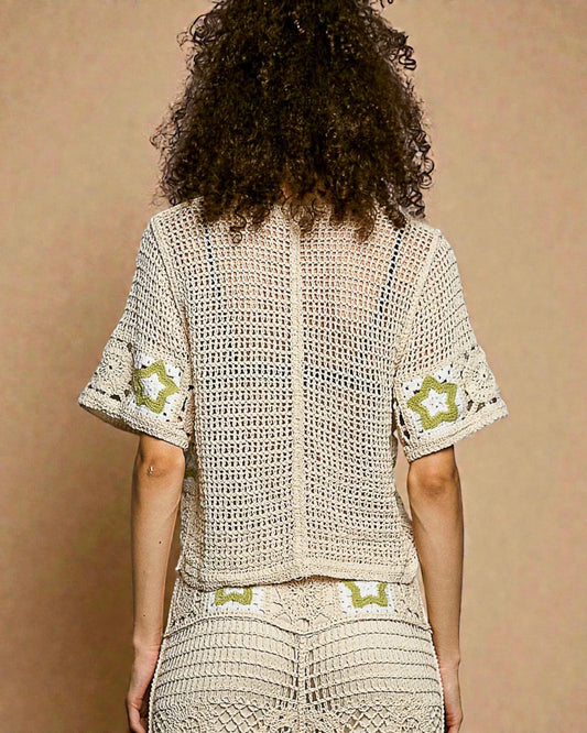 Person wearing a beige crochet outfit with green accents on a brown background