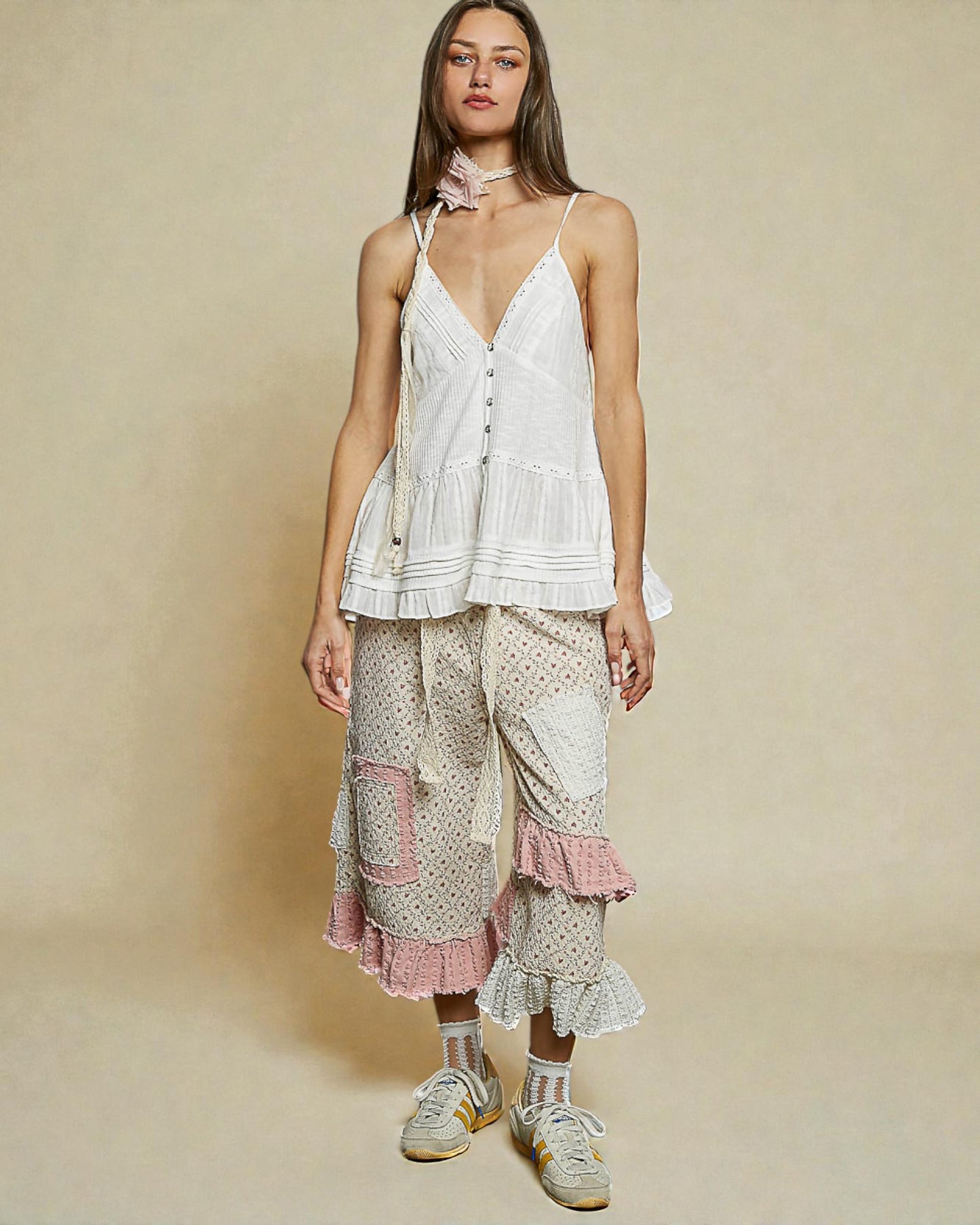 Woman wearing a white top and patterned pants on a beige background